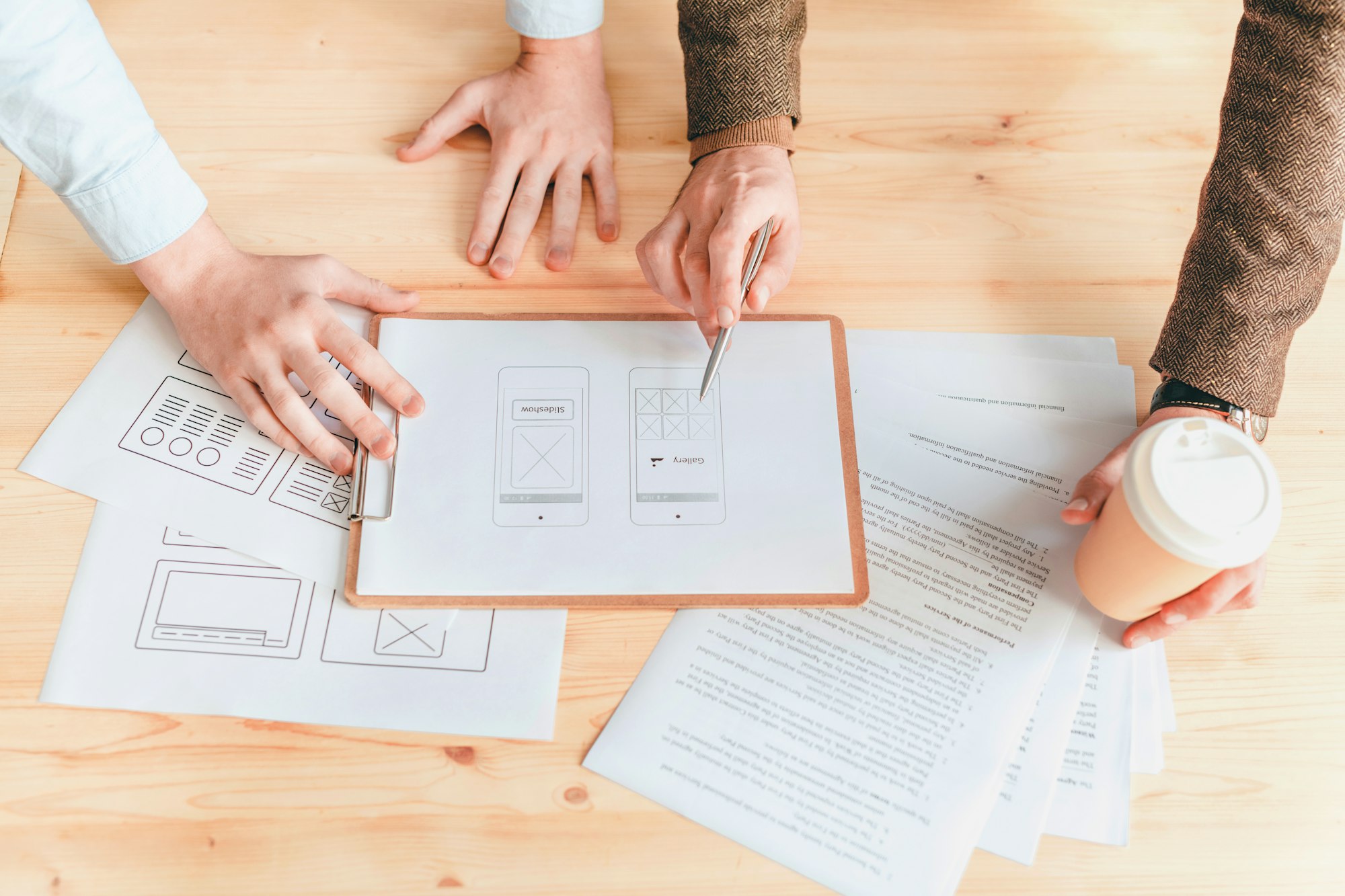 Hands of two programmers discussing one of papers with software application